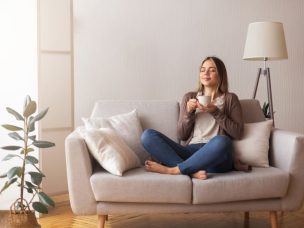 Finally coffee. Young coffee lover sniffing hot drink at cozy home interior, empty space